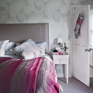 bedroom with white door and wallpaper walls
