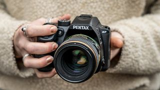 a Pentax KF held in the hand of a female photographer