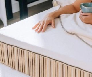 A hand resting on an Essentia mattress.