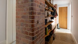 narrow hallway with exposed brick walls and wall shelves