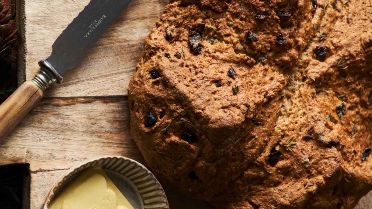 Loaf of bread on wood board with serrated knife