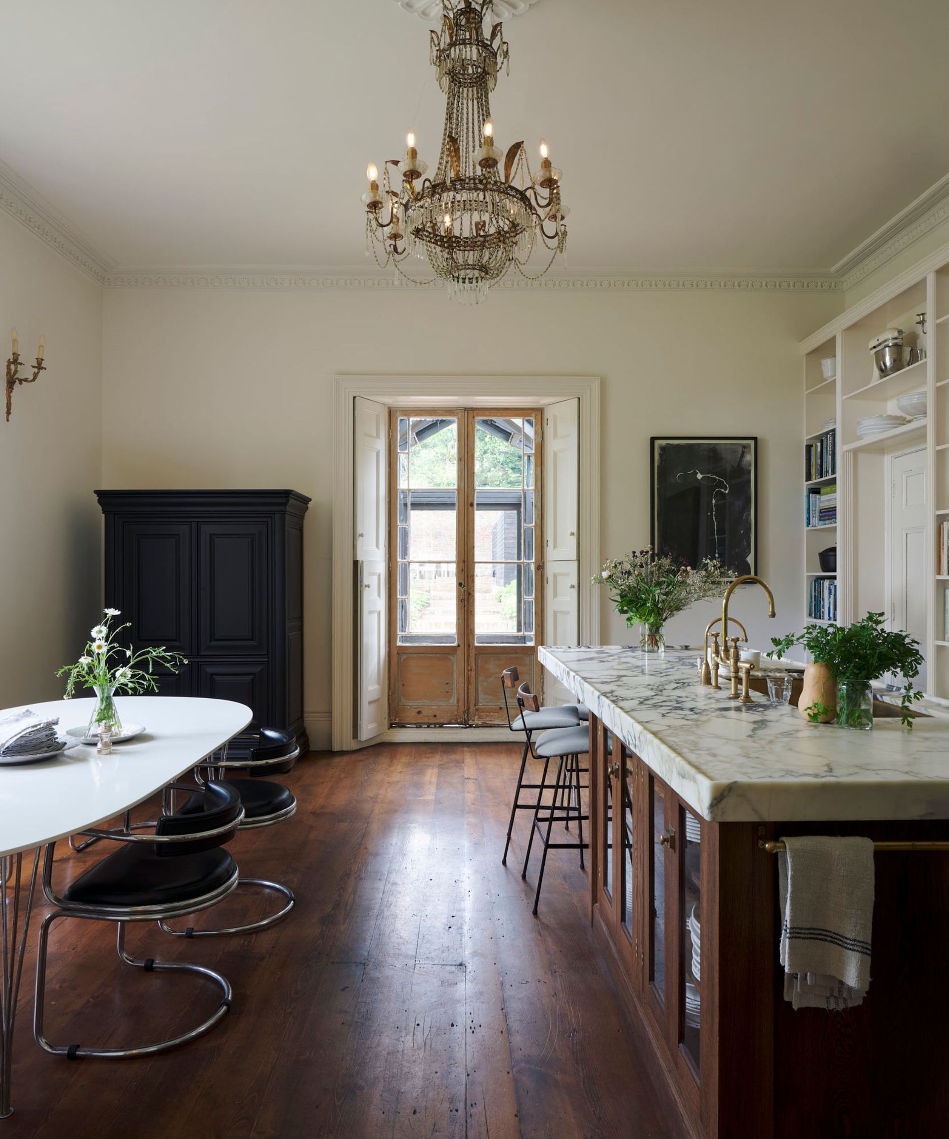 A kitchen with exposed wooden floors, a marble kitchen island and french doors to the garden
