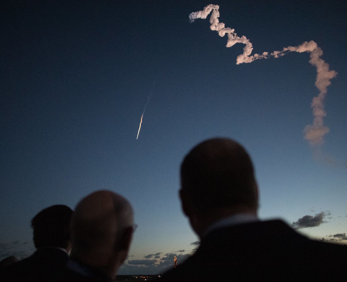 A United Launch Alliance Atlas V rocket carrying Boeing&#039;s CST-100 Starliner spacecraft soars into space after launching from Cape Canaveral Air Force Station in Florida on Dec. 20, 2019. Down below, Florida Gov. Ron DeSantis, left, ULA president and CEO Tory Bruno and NASA Administrator Jim Bridenstine observe from NASA&#039;s Kennedy Space Center.