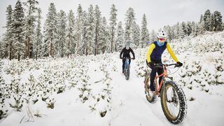 Two people fat biking across snowy terrain