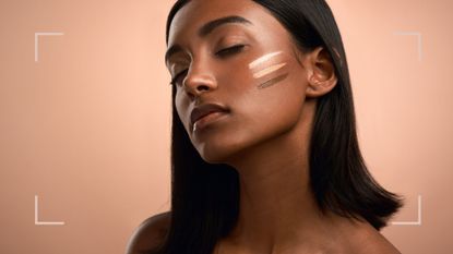 A woman using makeup to cover scars, with three swatches of foundation on her cheeks on a peach backdrop