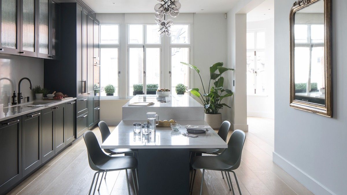 View of kitchen with white walls and dark green cabinets with vintage mirror fixed to dining area wall