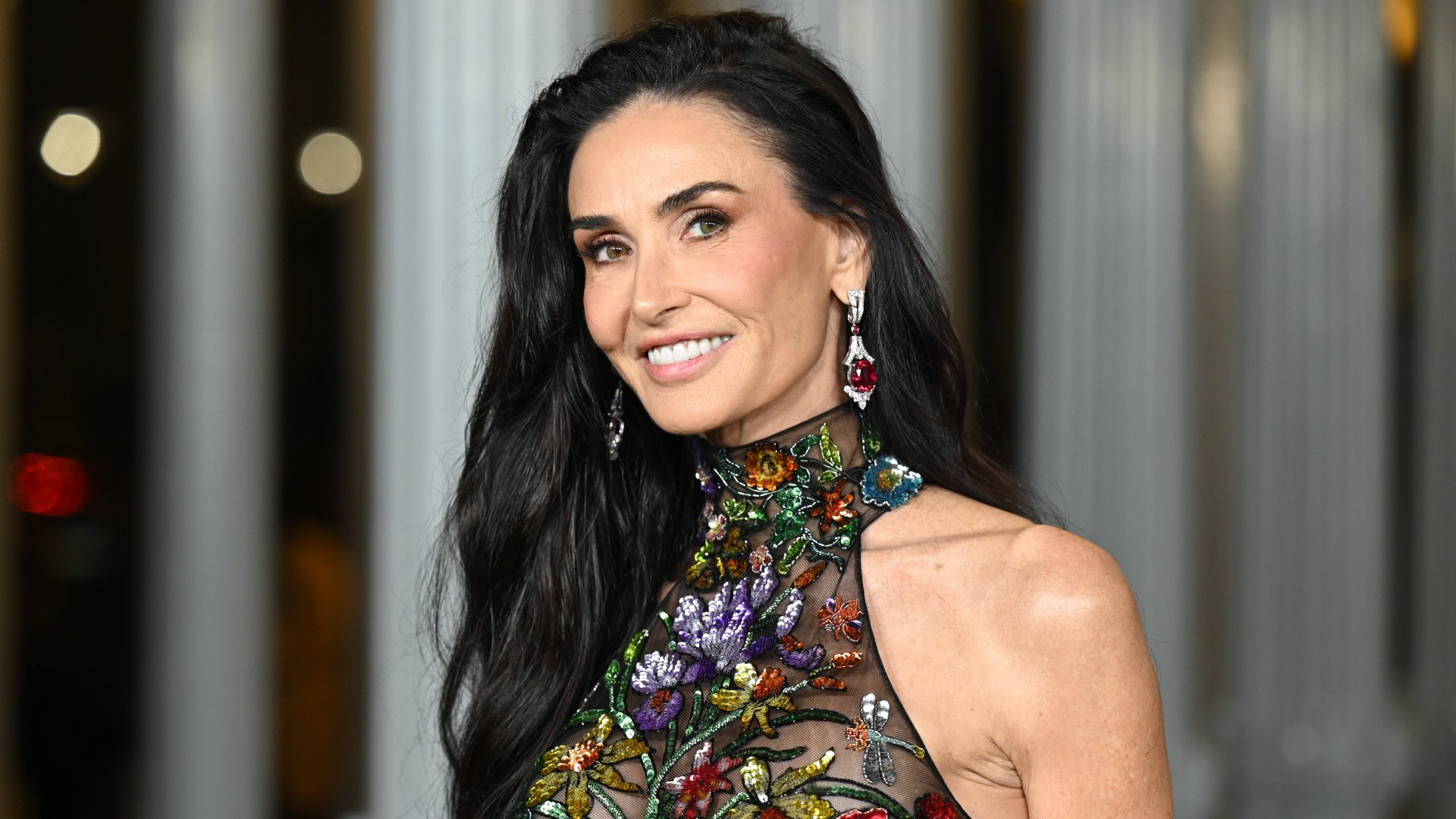 a close up photo of a white woman with long dark hair posing for paparazzi at a red carpet event