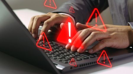 security warning icon floating above a laptop