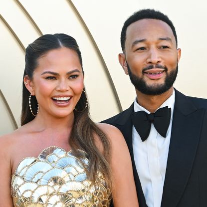 Chrissy Teigen and John Legend in formal wear in front of gold background