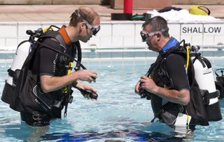 Prince William, Duke of Cambridge makes safety checks with BSAC Chairman Eugene Farrell before he scuba dives with British Sub-Aqua Club (BSAC) members