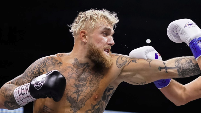 Jake Paul, with blonde hair and black gloves, throws a left ahead of the Jake Paul vs Mike Perry live stream