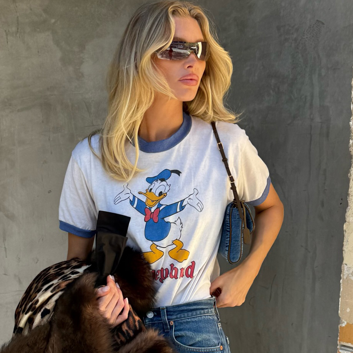 Elsa Hosk wearing a Disney T-shirt, Valentino leopard-print coat, bootcut jeans, and brown kitten heels from The Row.