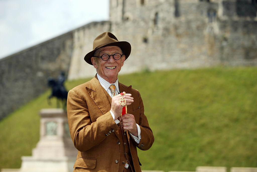 British actor Sir John Hurt poses after being awarded a knighthood by Queen Elizabeth II