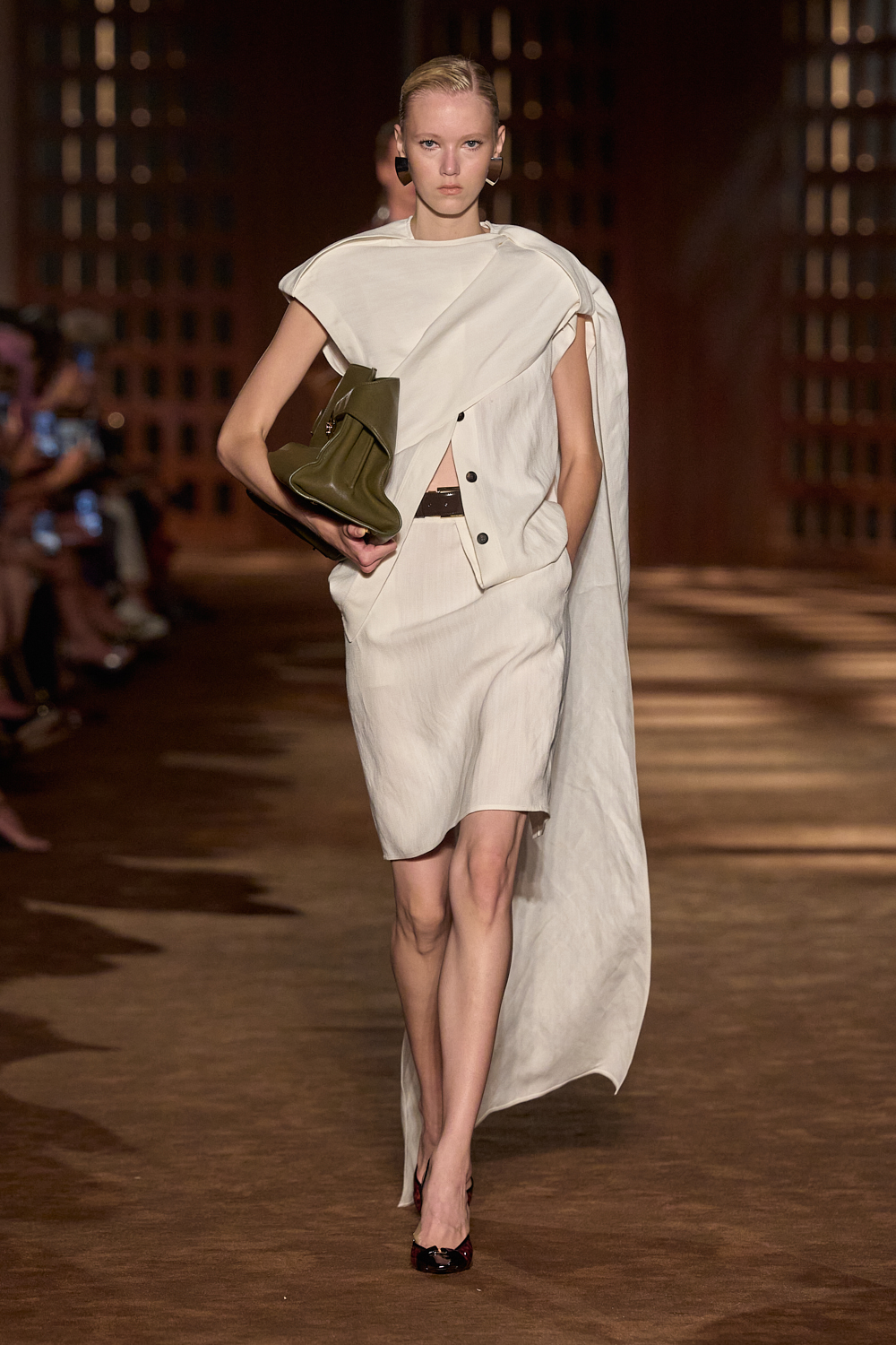 a woman carries a clutch bag at the ferragamo spring 2027 show.