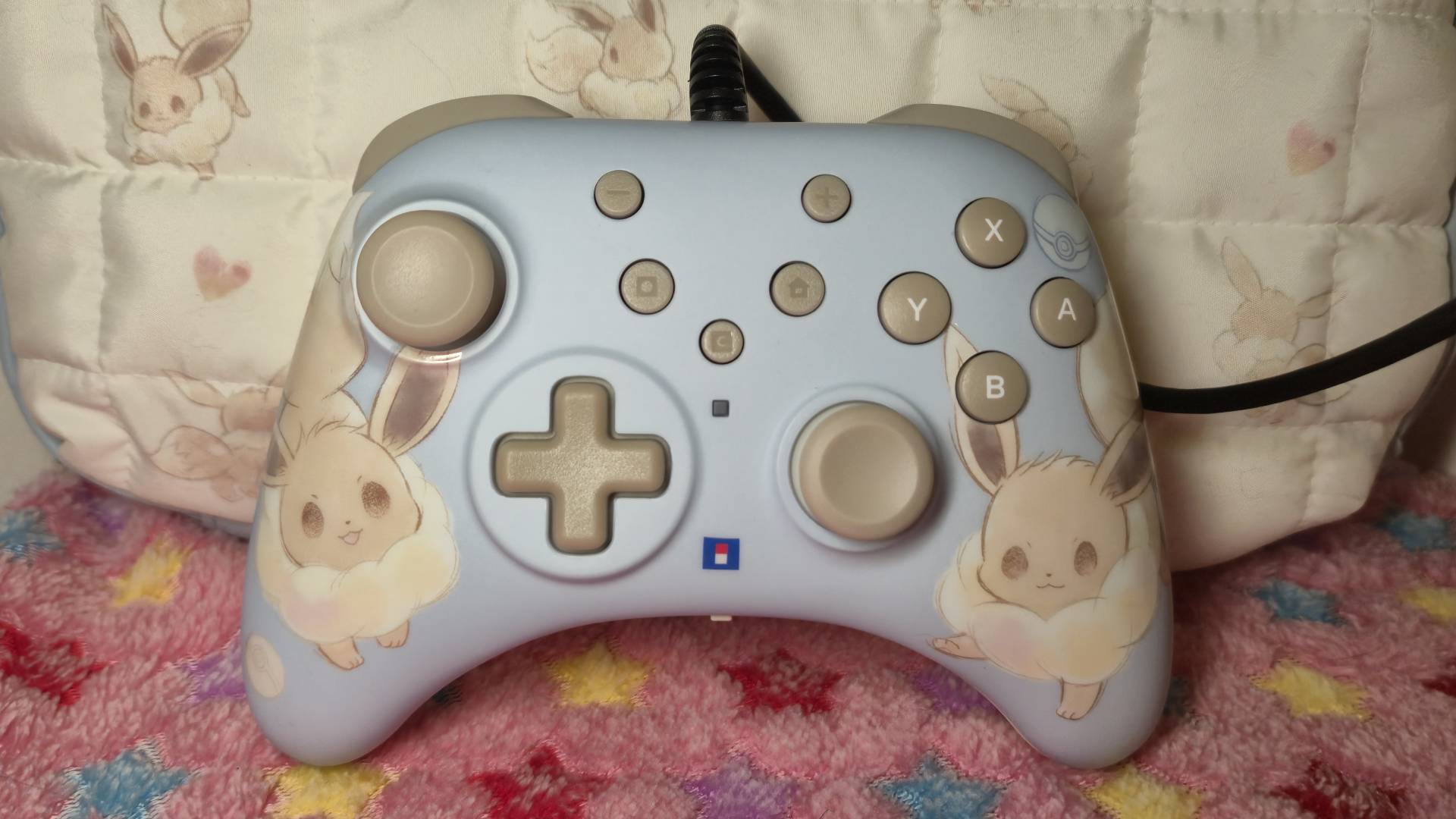 Photo of the Eevee Cottage Core HORIPAD Turbo Switch 2 controller sitting on a pink blanket.