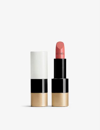 Hermes lipstick against grey background. one image shows the closed tube in white (top layer), black (middle layer) and gold (bottom layer), the second image is of the open tube showing a pink lipstick with Hermes embedded on it.