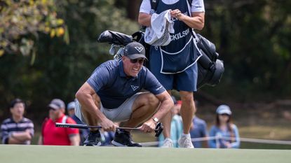 Phil Mickelson bends down to read a putt