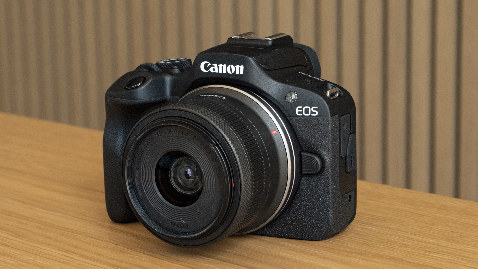 Canon EOS R100 camera on a table angled front