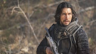 Mills (Adam Driver) holding a futuristic rifle in 65