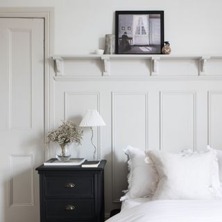 White bedroom with panel moulding feature wall, shelf, bedside table