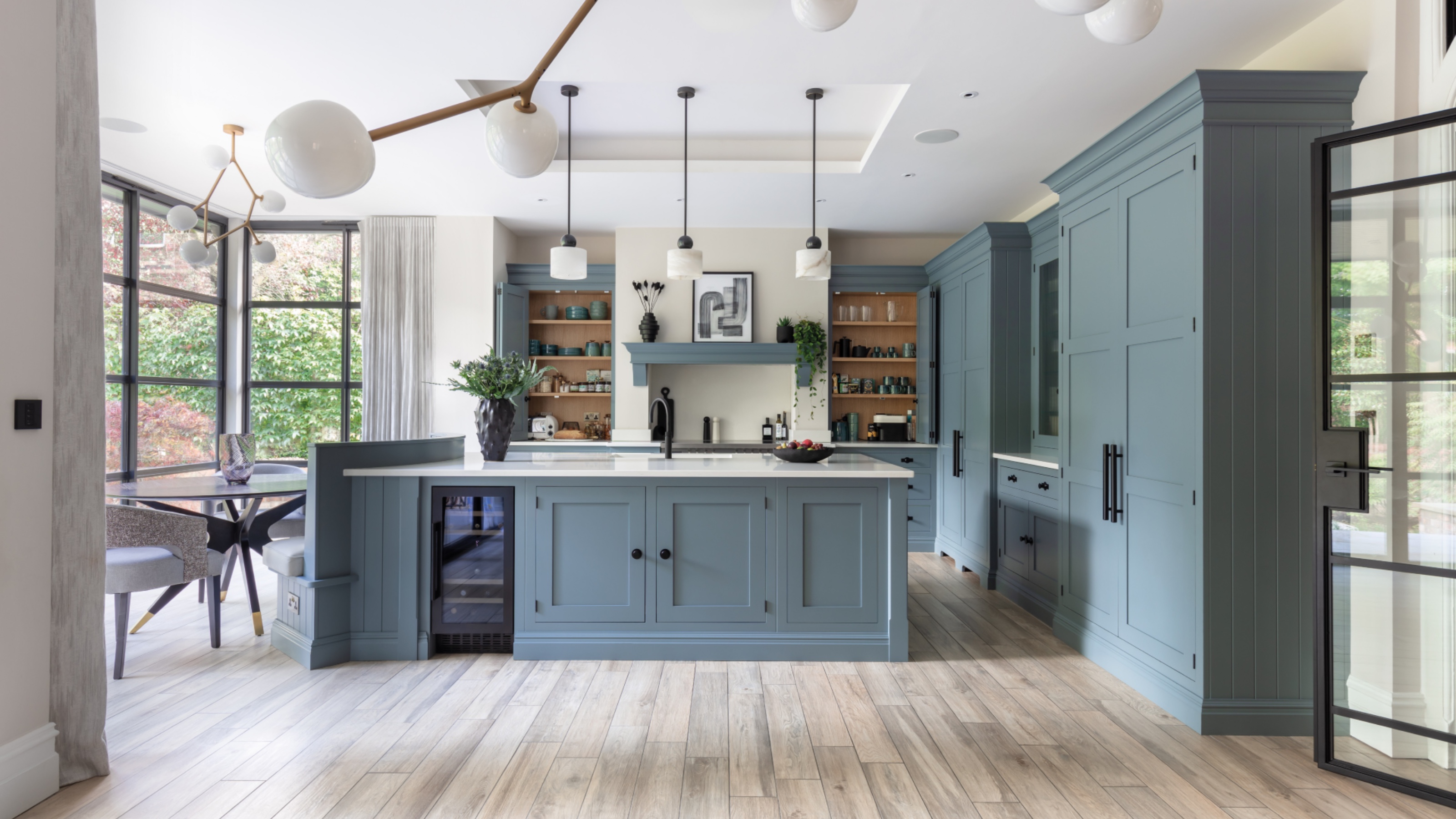 blue kitchen with banquette seating, globe lights, storage solutions, large kitchen island