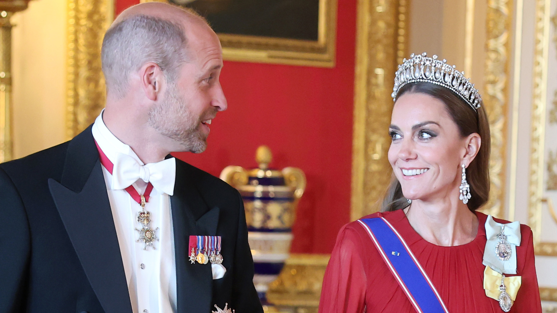 Kate Middleton wearing a red gown and tiara walking with Prince William at a state banquet