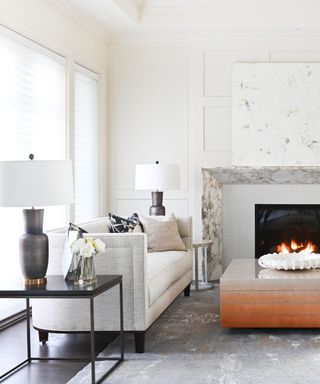 A white living room with a white sofa, fireplace and gray rug