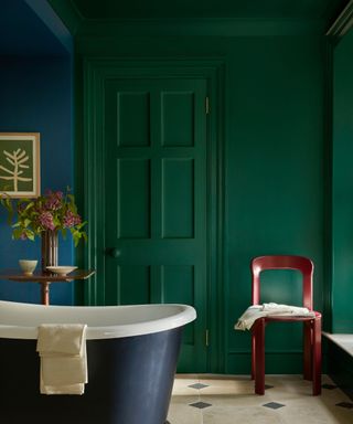 bathroom with dark green walls and navy blue roll-top bath