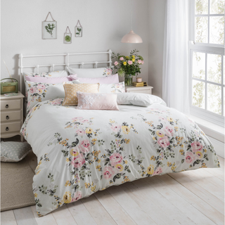 bedroom with white wall and floral bedsheet and pillows on bed
