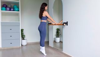 Woman in sportswear standing on her tiptoes in an exercise studio