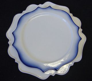An intricately-shaped white plate with a white and blue plate on top