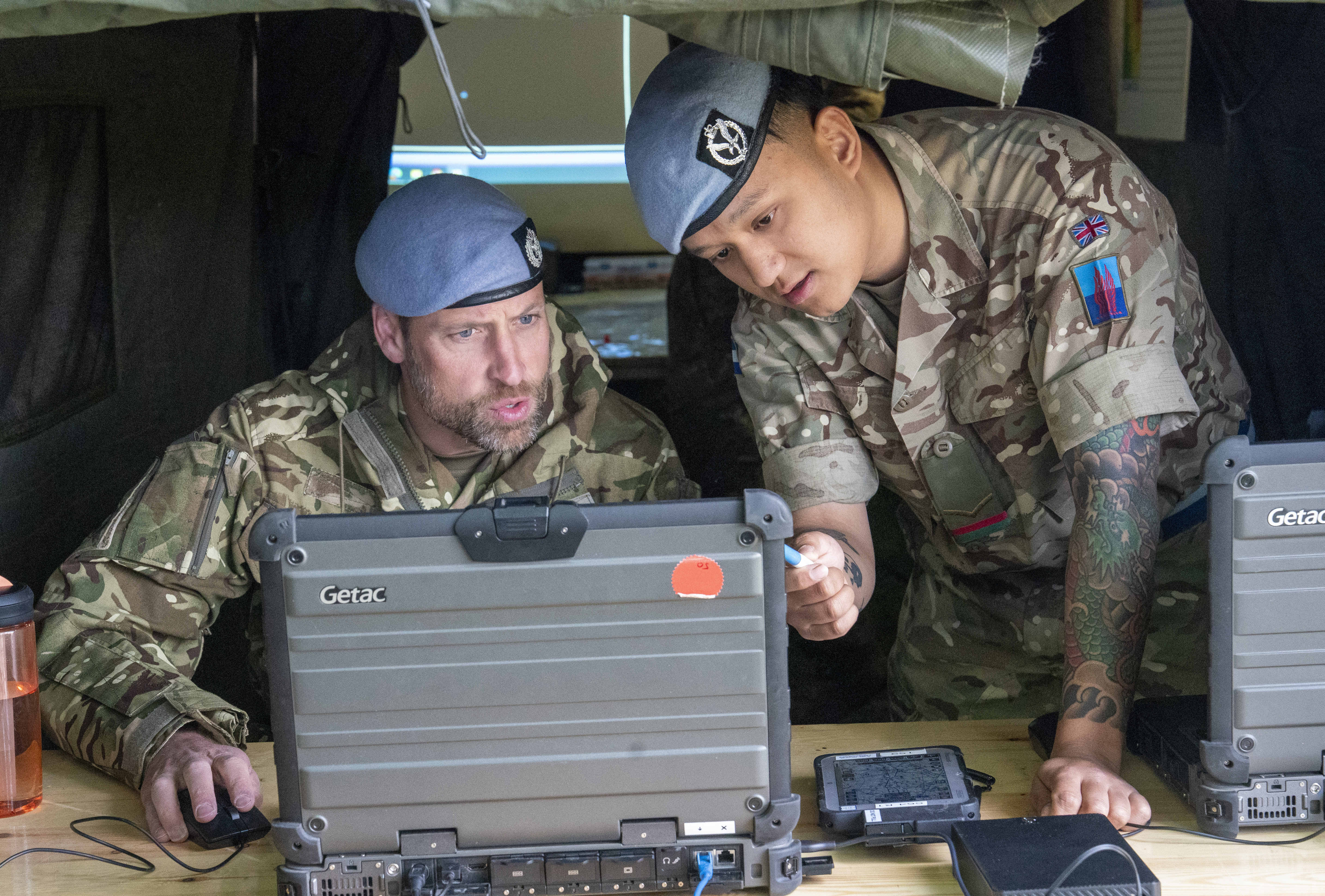 Prince William looking on a computer with a soldier