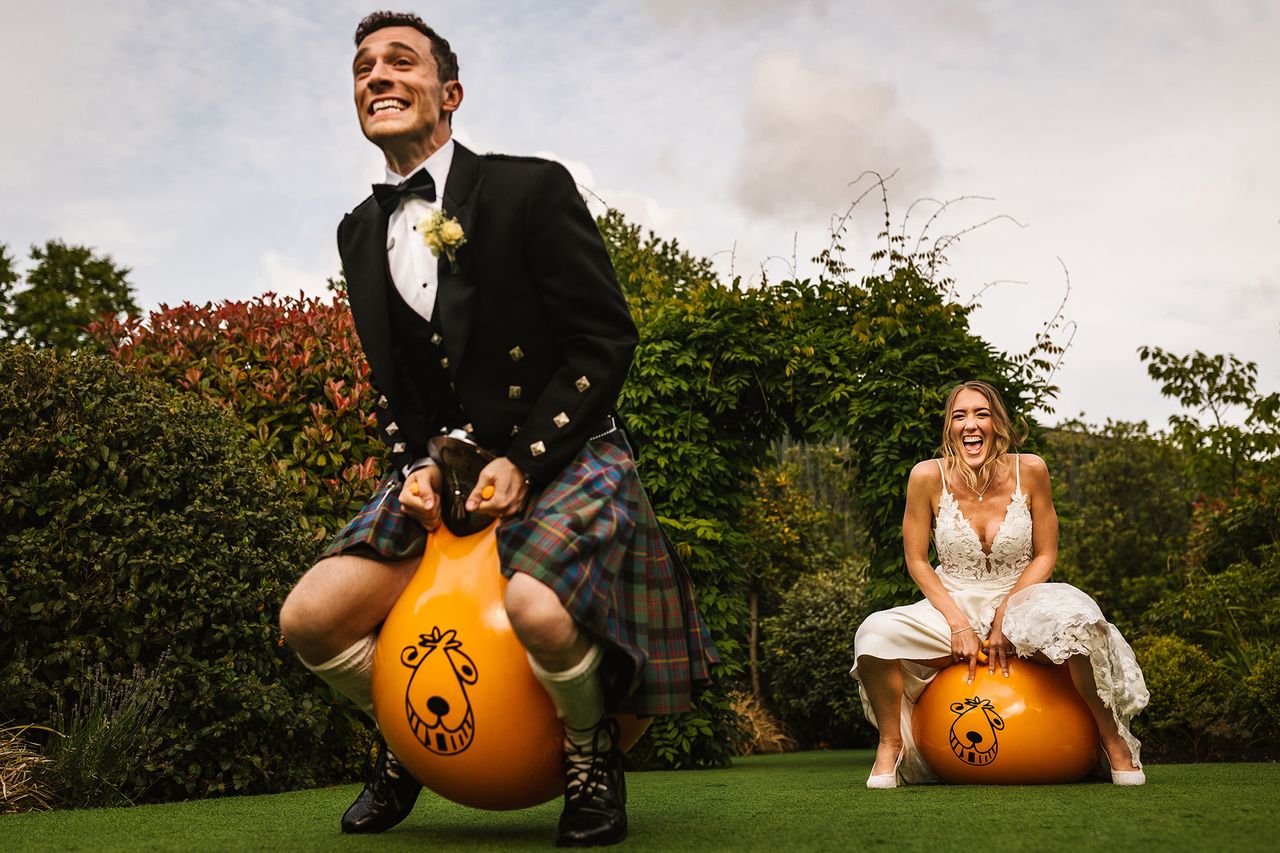 Photo taken by Steve Grogan and titled Bounce! It shows a bride and groom bouncing on space hopper inflatables during their wedding at Owen House Barn in Cheshire, UK.