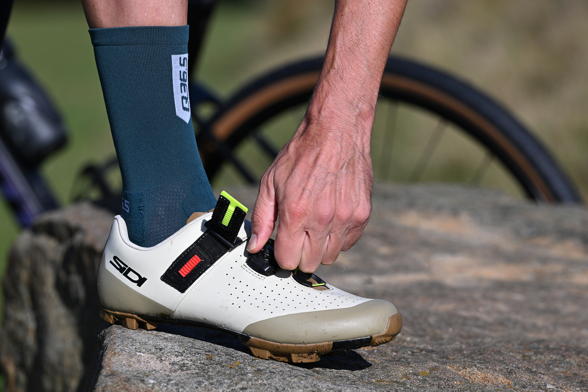 close up of a man fastening the dial on a beige Sidi Physis shoe