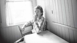 Bruce Springsteen seated at a kitchen table looking pensive