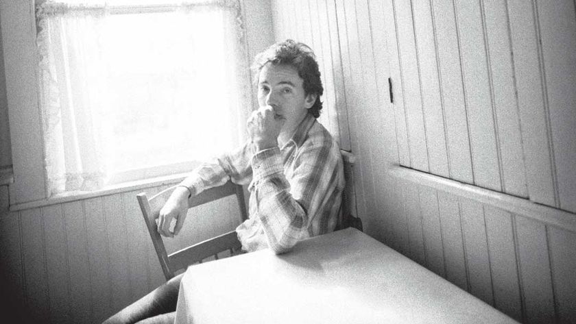 Bruce Springsteen seated at a kitchen table looking pensive
