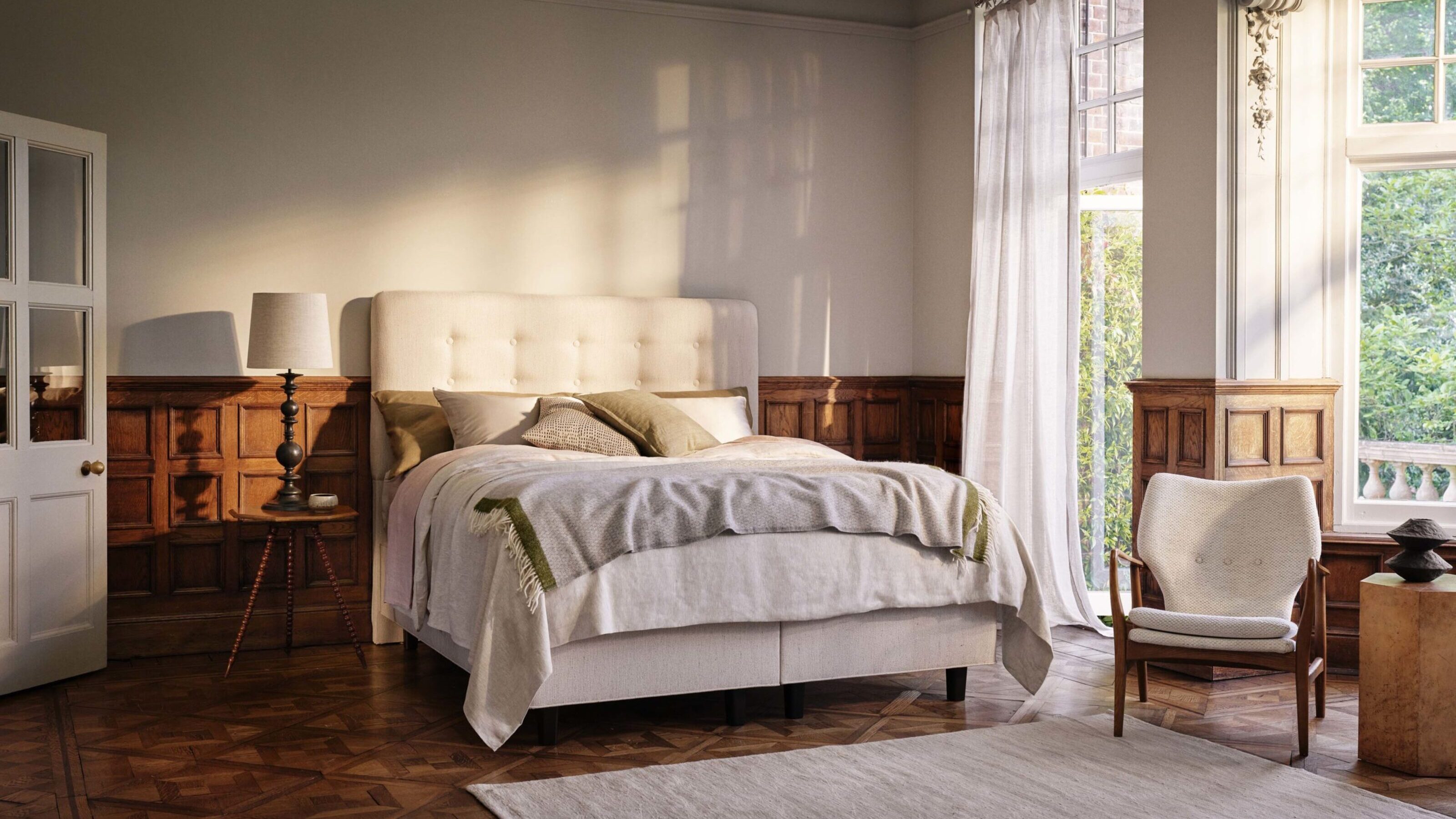 A bedroom with wooden panelling, parquet flooring, and a king size bed