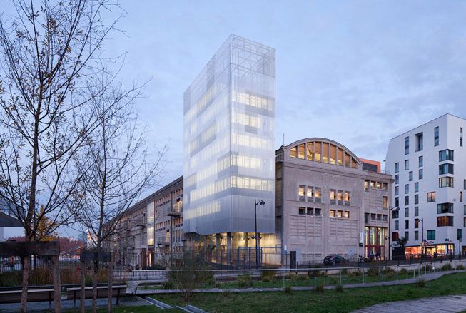 The Voltaire building photographed while still under construction. Multiple stores, rectangle-shaped building, with panoramic windows on each floor.