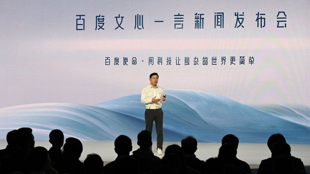 Baidu CEO Robin Li, standing on stage in front of large Chinese text at the Ernie Bot AI press event