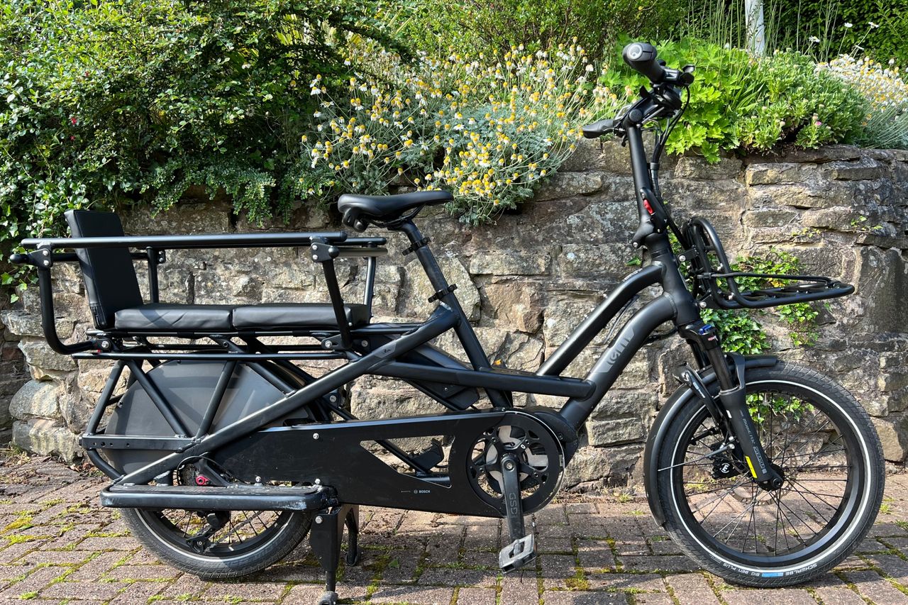 This image shows the Tern GSD side on in full with a stone wall and greenery behind, is one of the best electric cargo bikes on the market