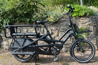 The Tern GSD side on in full with a stone wall and greenery behind, is one of the best electric cargo bikes on the market