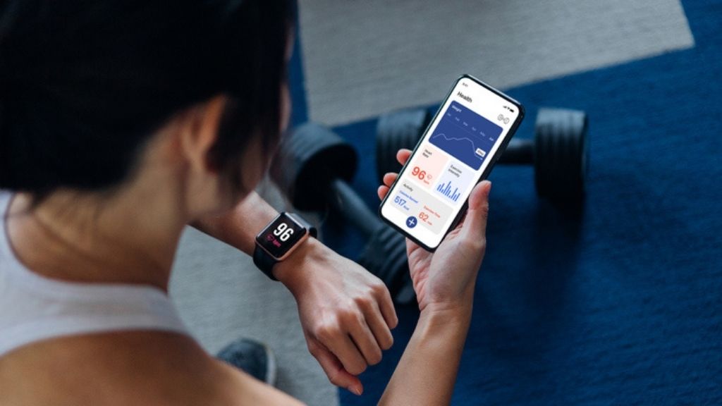 a women checking her pulse rate on her phone during a workout