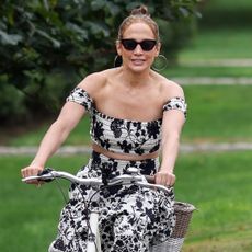 Jennifer Lopez on a bike wearing a Misa Los Angeles Hamptons floral skirt set and a pair of fisherman espadrille sandals