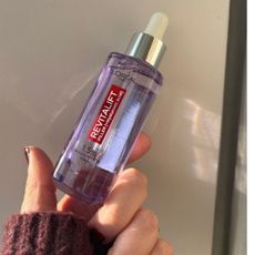 a hand holding loreal hyaluronic serum bottle