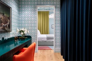 dressing room with blue wallpaper, teal dressing table and orange chair