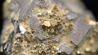 A close-up photo of a rock containing a raw gold nugget in a mine.
