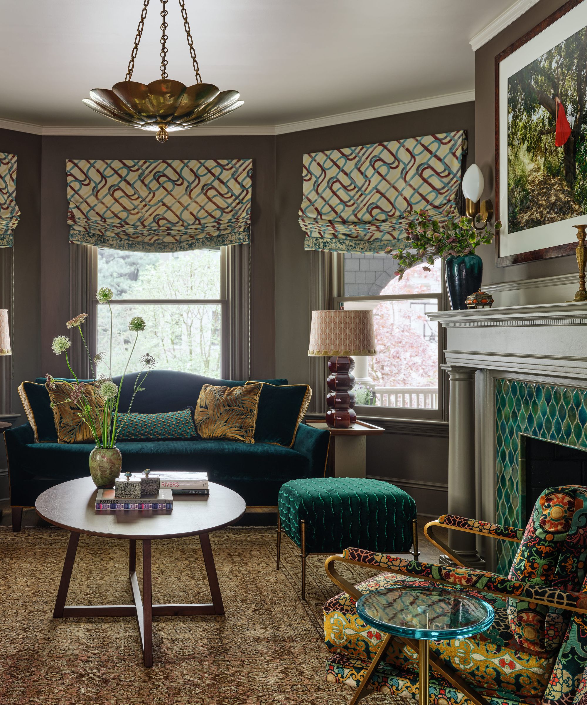 Eclectic living room with a teal velvet sofa, patterned armchair, and a fireplace with green tiled detailing.