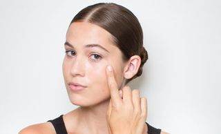 woman applying concealer to face