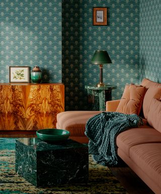 teal and tangerine living room with tangerine couch, marble coffee table, teal wallpaper, sideboard, green table lamp, green throw