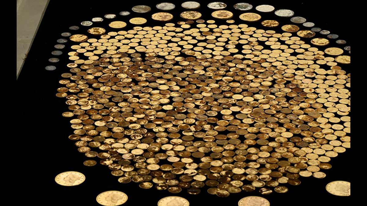 We see hundreds of gold and silver coins against a black background.